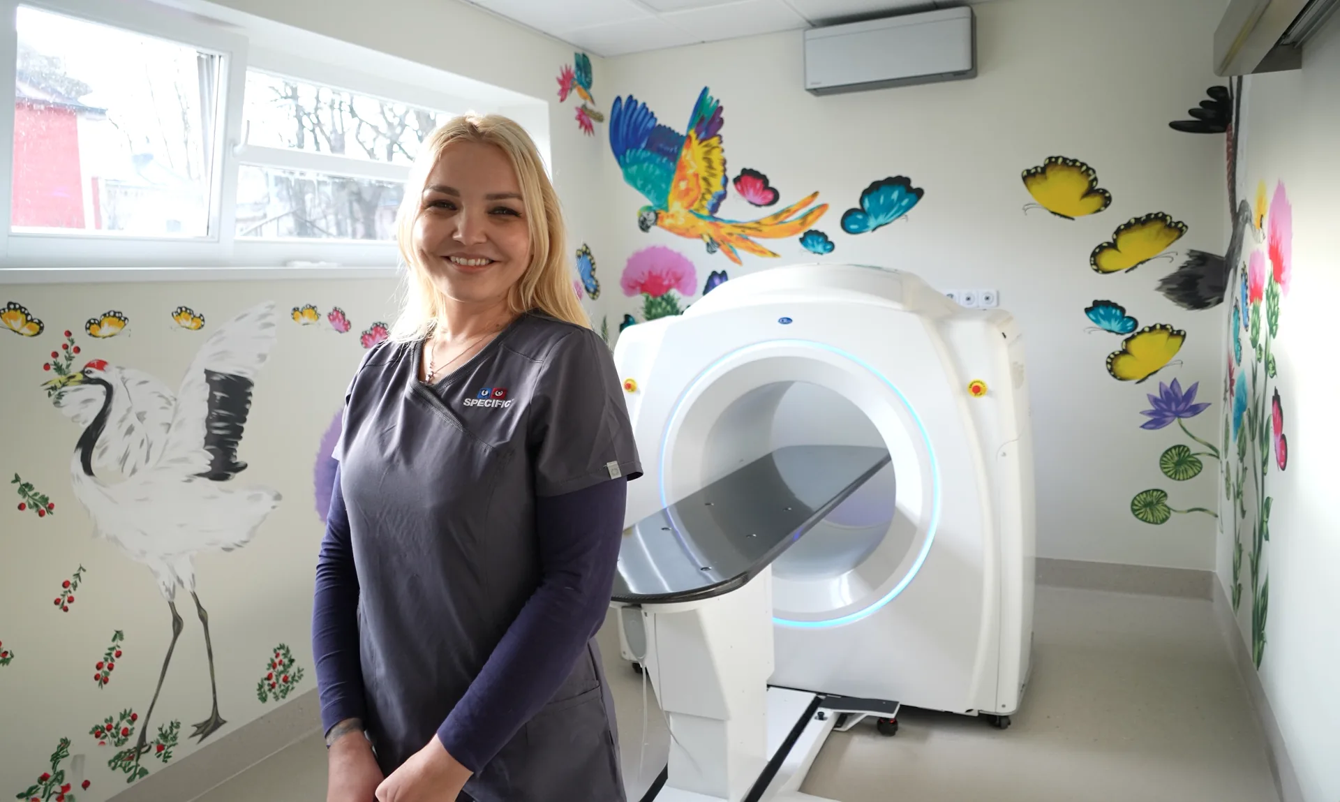 A veterinary technologist beside a CT scanner in a treatment room